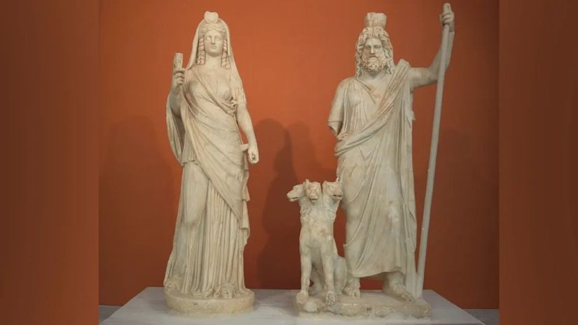 Στην απεικόνιση ο θεός του Κάτω Κόσμου, Άδης, με τη γυναίκα του, Περσεφόνη και ανάμεσά τους ο Κέρβερος.