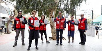 Οι άνθρωποι της INTERAMERICAN, με το γιλέκο του πωλητή του περιοδικού «σχεδία» και το περιοδικό ανά χείρας.